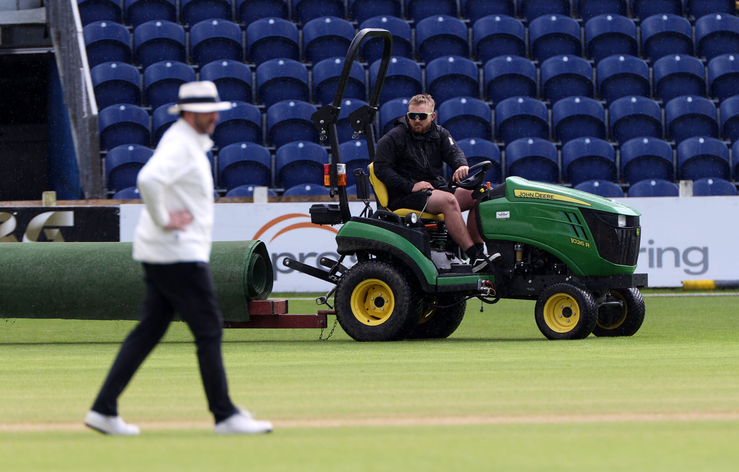 Man on small tracker towing pitch covering