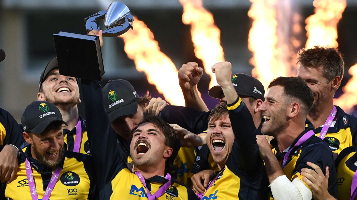 Glamorgan County Cricket Club team members holding a trophy aloft and cheering, with fireworks in background